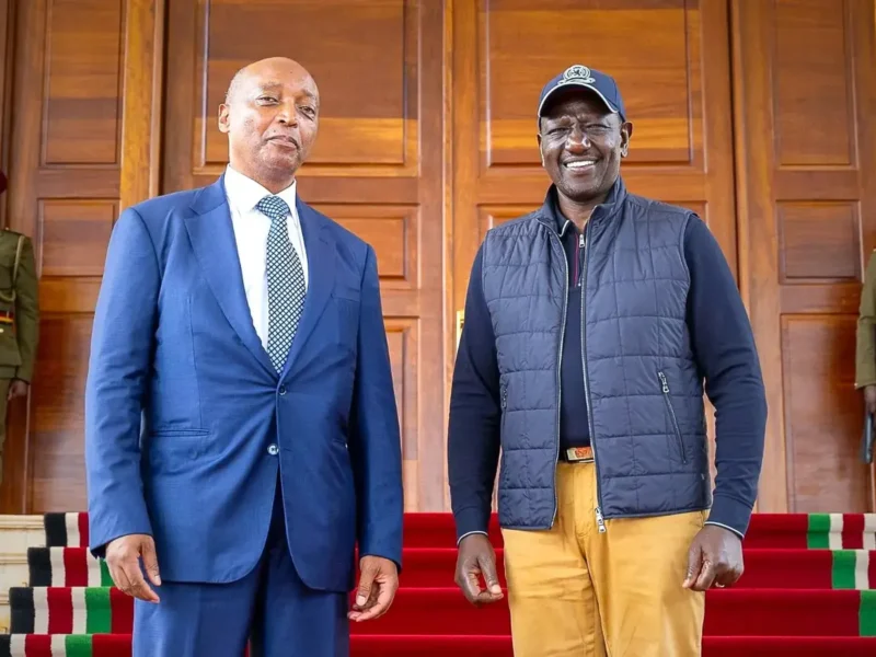 CAF President Patrice Motsepe in a blue suit standing beside President William Ruto in a cap and gilet