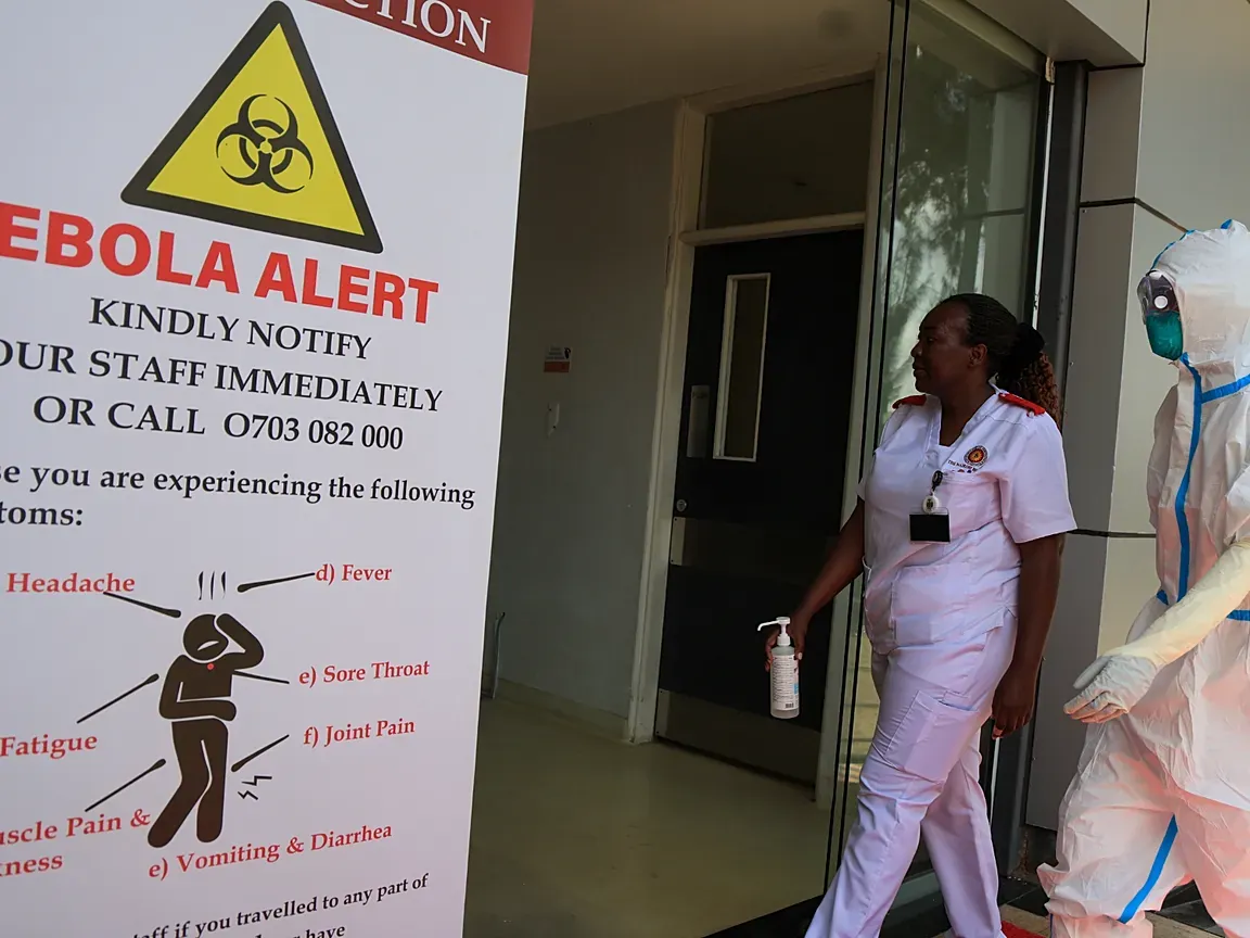 Health workers in protective gear beside an Ebola alert notice