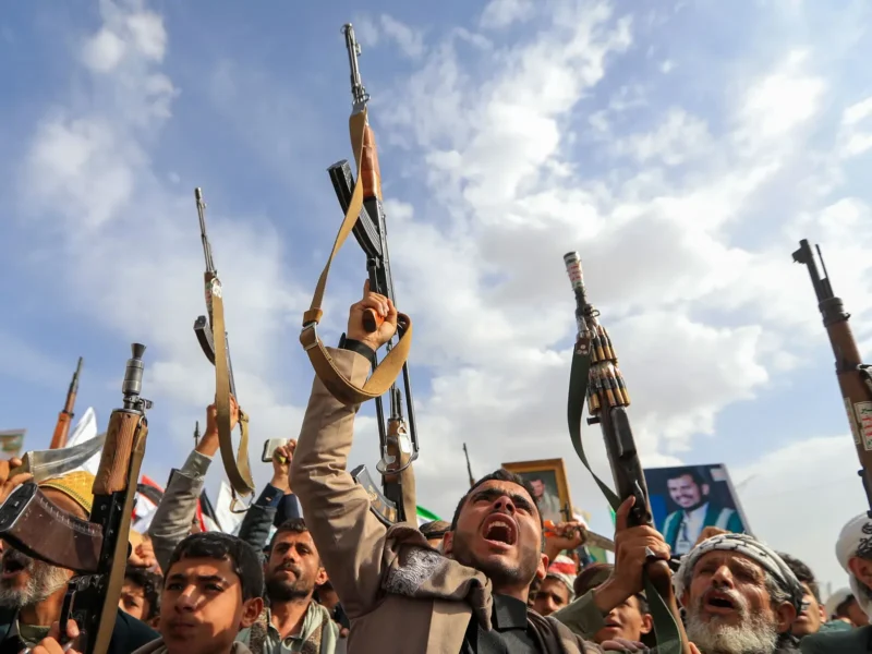 Crowd of armed men raising rifles at a rally
