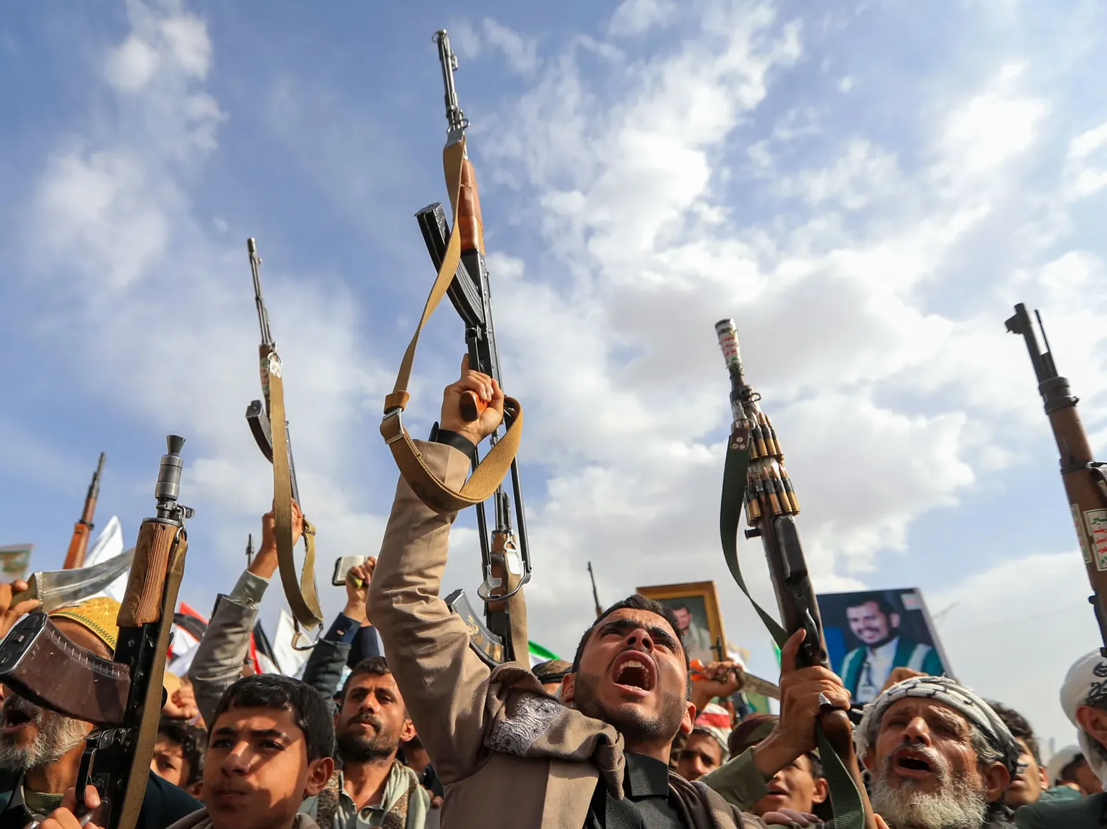 Crowd of armed men raising rifles at a rally