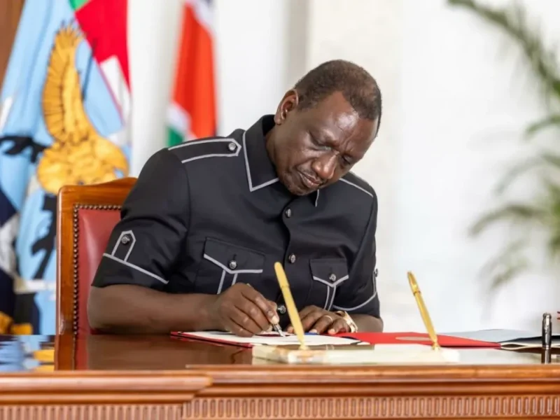 President William Ruto signing documents at a desk