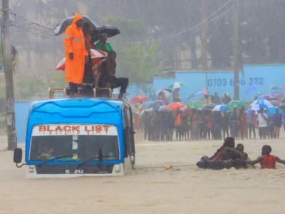 People wading through a flooded road as a bus passes